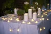 An outdoor table setting at dusk, decorated with LED string lights and pillar candles. Náhled obrázku produktu