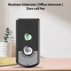 A black intercom device with a green call button and a large 'TALK' button is placed on a wooden surface. A potted plant is visible in the background. Podgląd zdjęcia produktu