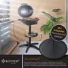 An electric grill is shown on a stand with a lid open, cooking food. There is a plant in the background and a power outlet on the wall. Produktbild-Vorschau