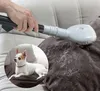 A hand is using a vacuum attachment to remove pet hair from a couch cushion, with a small dog in a circular inset. Náhled obrázku produktu