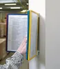 A hand is shown interacting with a wall-mounted display system in what appears to be a warehouse or industrial setting. Anteprima dell’immagine prodotto