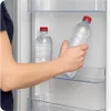A person's arm is reaching into a refrigerator to take out a bottle of water. Náhľad obrázku produktu