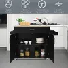 A black kitchen cart with a wooden top is shown in a kitchen setting. The cart has its doors open, revealing shelves with various items like bowls, cups, and jars. Anteprima dell’immagine prodotto