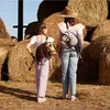 Two people wearing hobby horse backpacks in a hay barn. Anteprima dell’immagine prodotto