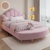 A pink upholstered bed with a shell-shaped headboard and a matching curved bench at the foot of the bed, in a child's bedroom. Produktbild-Vorschau