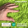 A hand is shown pressing into a soft, fluffy green carpet or rug. There are logos and text overlays. Anteprima dell’immagine prodotto