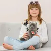 A young girl sitting on a couch holding a stuffed animal. Voir les images du produit