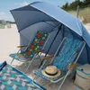 Two beach chairs under a large blue umbrella on a sandy beach. Anteprima dell’immagine prodotto