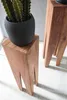 A close-up shot of two wooden plant stands, one with a black pot and a green plant on top. Náhled obrázku produktu