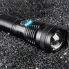 A close-up shot of a black LED flashlight resting on a dark, granular surface. Anteprima dell’immagine prodotto