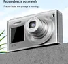 A silver digital camera is placed on a gray surface with a blurred blue sky background. Produktbild-Vorschau