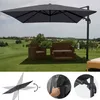 An outdoor patio scene with a large cantilever umbrella providing shade over rattan furniture, set against a green landscape with rolling hills and a distant village. Produktbild-Vorschau