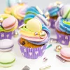 A close-up of several colorful cupcakes decorated with macarons and sprinkles. Náhled obrázku produktu