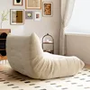A beige beanbag chair is placed on a patterned rug in a room with framed artwork on the wall and a window with blinds. Produktbild-Vorschau