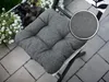 A grey cushion on a chair outdoors, next to a planter with white flowers. Produktbild-Vorschau