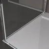 A close-up view of a shower enclosure corner, showing the glass and metal frame against a dark floor and a light gray wall. Voir les images du produit