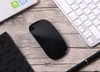 A black computer mouse is placed on a wooden desk next to a keyboard and a laptop. Produktbild-Vorschau