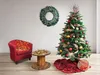 A decorated Christmas tree with ornaments and lights, a red armchair with lights, a wooden spool table with lights, and a wreath on the wall. Produktbild-Vorschau