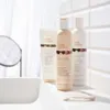 Three Milk Shake hair care products are arranged on a white surface in front of a tiled wall. Anteprima dell’immagine prodotto