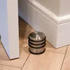 A doorstop on a wooden floor next to a white door and skirting board. Náhled obrázku produktu