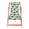 A wooden deck chair with a light blue fabric featuring a pattern of cartoon bees. Náhled obrázku produktu