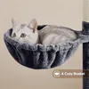 A cat is resting in a cozy basket attached to a cat tree. Produktbild-Vorschau