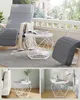 A collage showing a geometric white side table on a rug, next to a rocking chair on a balcony, and two close-ups of the table styled with books and decor. Produktbild-Vorschau