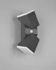 A modern, geometric wall light fixture mounted on a plain gray wall. Anteprima dell’immagine prodotto