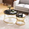 Two round coffee tables with black marble-look tops and gold metal bases are placed on a rug in a living room setting. A sofa is visible in the background. Náhľad obrázku produktu