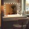 A vanity mirror with lights on a dressing table, with a chair in the foreground. Produktbild-Vorschau