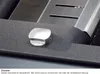 A close-up view of a silver button on a textured gray surface, with metallic elements in the background. Produktbild-Vorschau