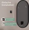 Back of an oval mirror with mounting hardware and a power cord, next to a wall with an electrical outlet and text overlays describing installation features. Produktbild-Vorschau
