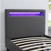 A close-up view of a gray upholstered bed frame with integrated purple LED lighting. Produktbild-Vorschau