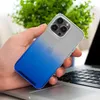 A hand holding an iPhone 14 Pro Max with a gradient blue and clear case, placed on a laptop keyboard with a plant in the background. Produktbild-Vorschau