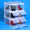 A stack of clear plastic shoe storage boxes with various shoes inside, against a blue background. Produktbild-Vorschau