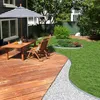 A backyard scene with a wooden deck, outdoor furniture, and a garden. Produktbild-Vorschau