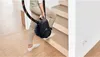 A person is carrying a black vacuum cleaner up a wooden staircase. Produktbild-Vorschau