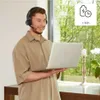 A man wearing a headset is using a laptop in a well-lit room with a window view of greenery. Anteprima dell’immagine prodotto