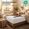A woman sleeping on a bed with a white fitted sheet. Produktbild-Vorschau