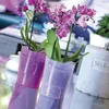 Two potted orchids in decorative purple and light purple vases, with a concrete planter labeled 'Welcome' in the background. Podgląd zdjęcia produktu