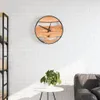 A round wall clock made of wood and iron hangs on a white brick wall above a small white table with a plant. Anteprima dell’immagine prodotto
