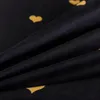 A close-up view of black fabric with golden heart patterns, showing the texture and folds of the material. Produktbild-Vorschau