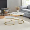 A living room scene featuring a nesting coffee table set with a marble-like top and gold metal legs, placed on a rug next to a sofa. Náhľad obrázku produktu