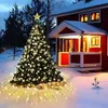 A decorated Christmas tree with lights and ornaments stands in the snow in front of a red house. Anteprima dell’immagine prodotto