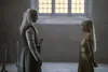 Two people with white hair stand facing each other in a large, dimly lit room with tall windows. Podgląd zdjęcia produktu