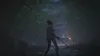 A person holding a sword in a dark, misty forest with a building in the background. Náhľad obrázku produktu