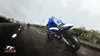 A motorcycle racer in a blue and white suit on a wet road during a race. Náhled obrázku produktu