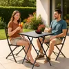 A couple enjoys drinks at a small outdoor bistro set on a patio. Produktbild-Vorschau