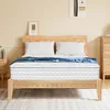 A mattress on a wooden bed frame with pillows and a blue blanket. Produktbild-Vorschau