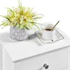 A white nightstand with a vase of yellow and white flowers and a cup of coffee on top. Podgląd zdjęcia produktu